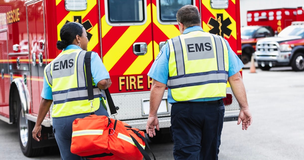 Two paramedics walk toward an ambulance