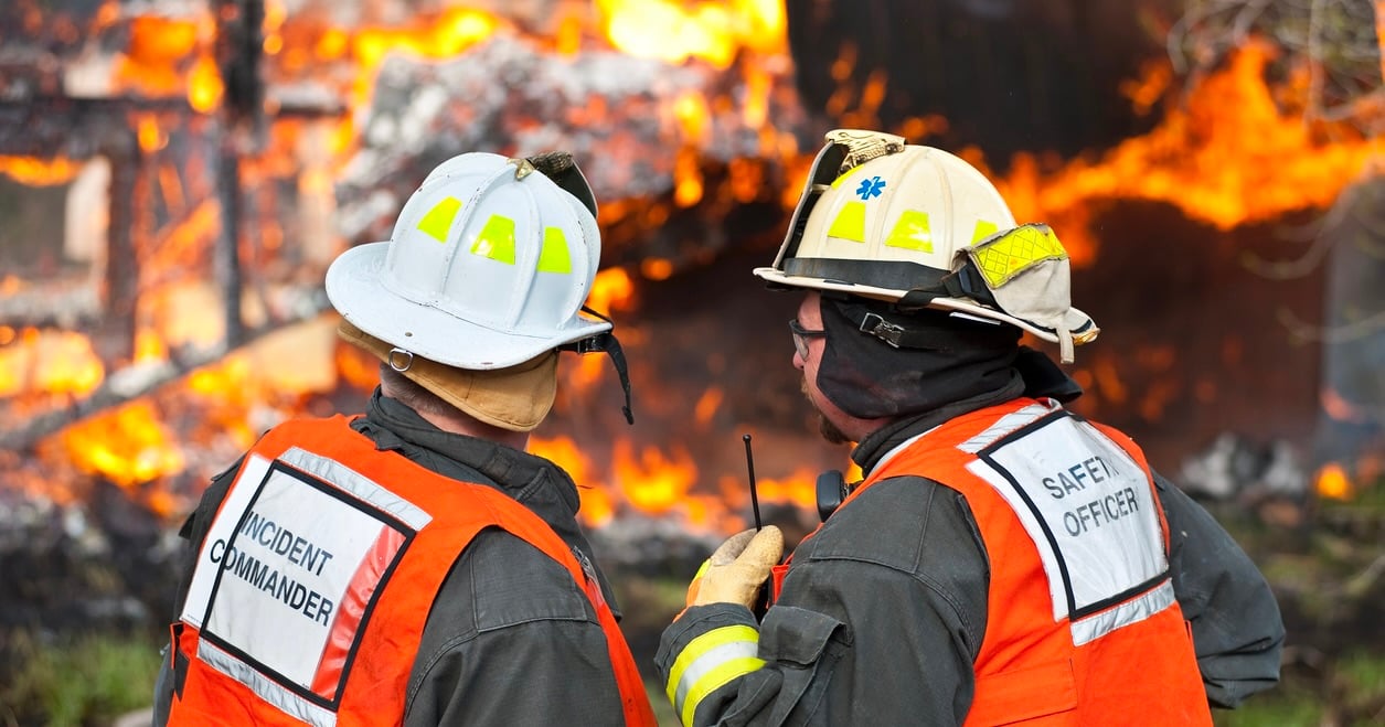 A fire department Incident Commander and Safety Officer strategizing on the scene of an active fire