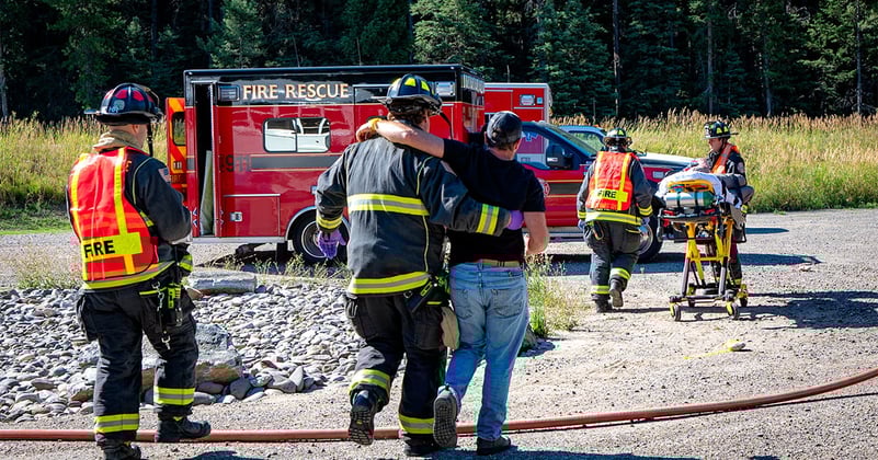firefighter helps a civilian walk during an emergency training exercise